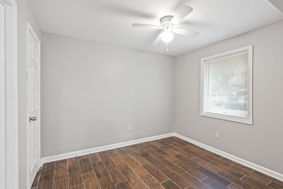 an empty room with a ceiling fan and a window