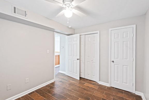 an empty living room with white doors and a ceiling fan