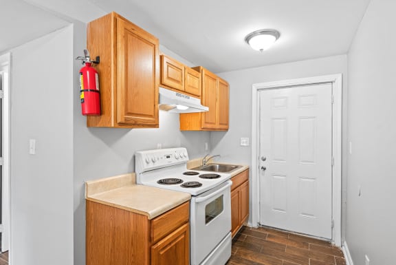 a kitchen with wood cabinets and white appliances and a white door