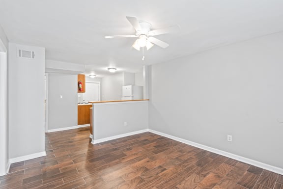 an empty living room with wood flooring and a ceiling fan