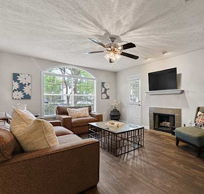 A living room with a brown couch, a fireplace, and a television.