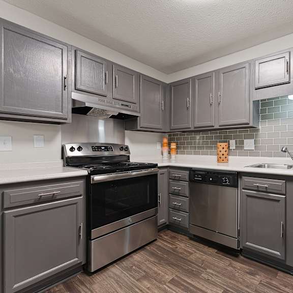 A kitchen with stainless steel appliances and grey cabinetry