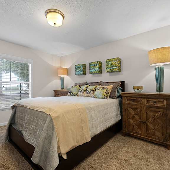 A bedroom with a bed, nightstand, and two lamps.
