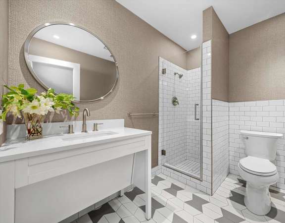 A white sink and toilet in a bathroom with a mirror and tiled walls.