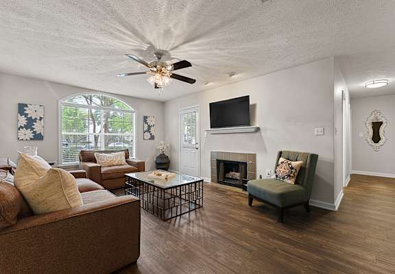 A living room with a brown couch, a fireplace, and a television.
