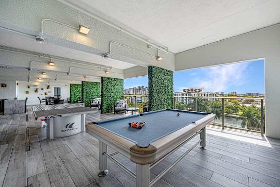 a games room with a pool table and a view of the city
