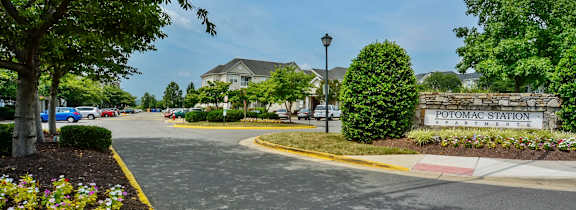 A large white building with a black roof is surrounded by trees with autumn leaves.