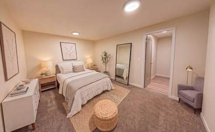 A bedroom with a large bed and a chair.