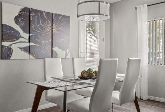 A dining table with four chairs and a decorative wall hanging.