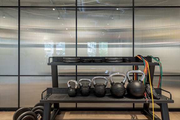 a rack with helmets and weights in a gym with glass walls