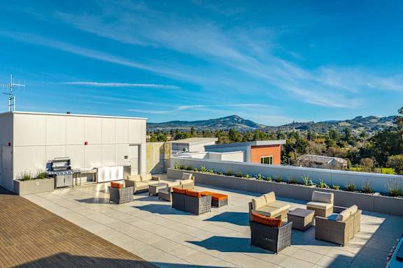 A rooftop patio with several couches and a table.