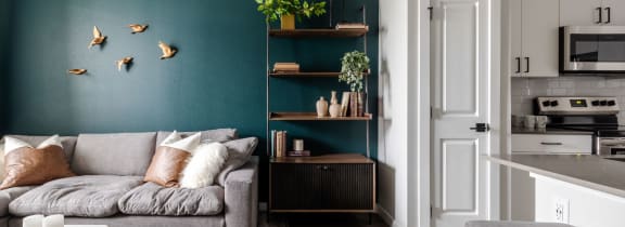 a living room with a green accent wall and a gray couch