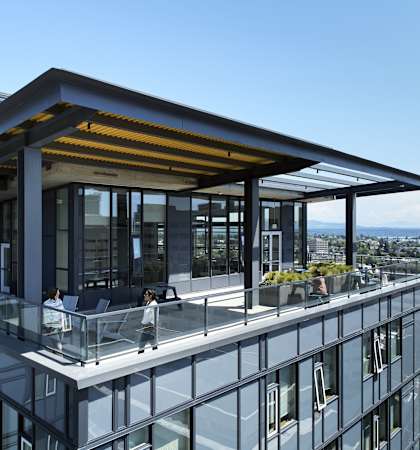A modern building with a glass balcony and a person walking on it.