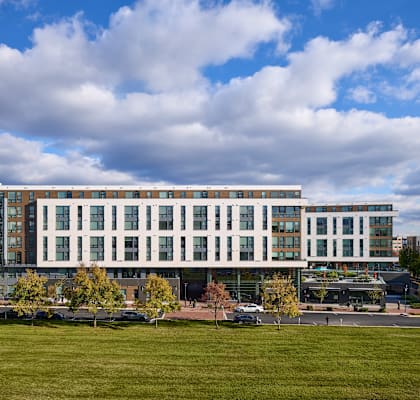 a large white building with a green field in front of it