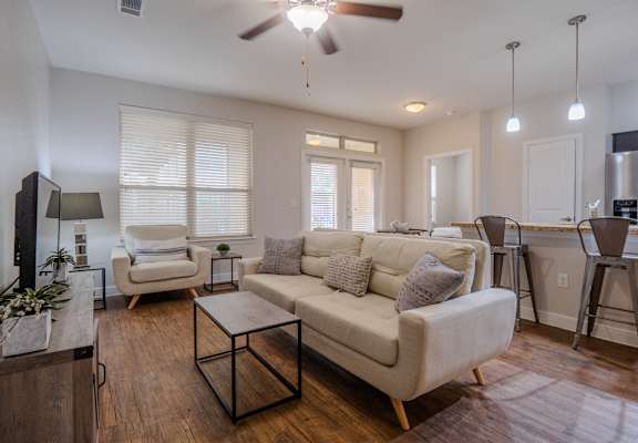a living room with a couch and a chair in front of a dining room table