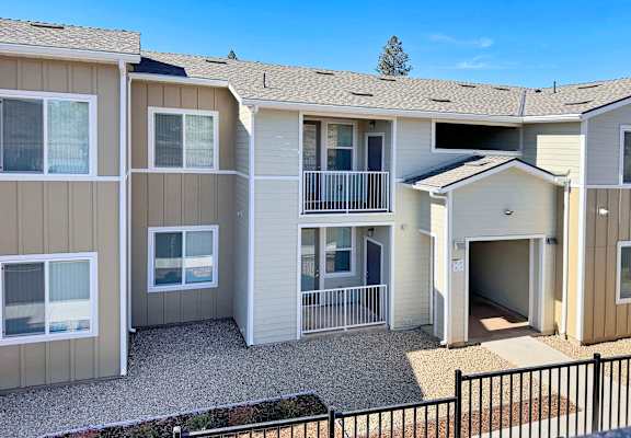 an exterior view of an apartment building with a driveway and balcony