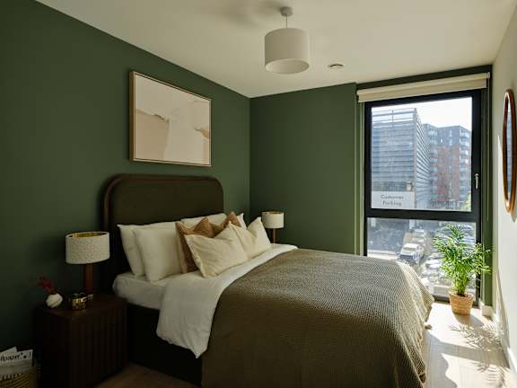 A bedroom with a large bed and a window overlooking a city street.