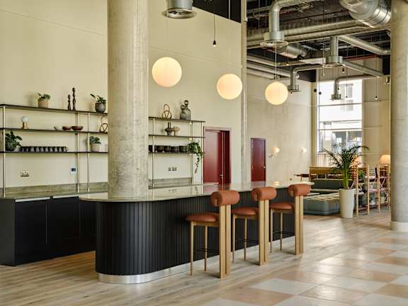A bar area with a black counter and wooden stools.