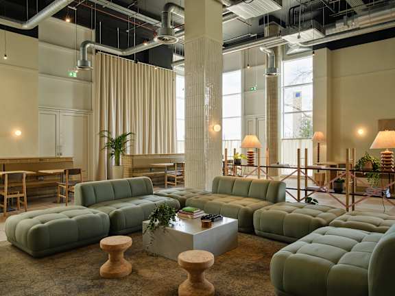 A room with a long green couch and a wooden table in front of it.
