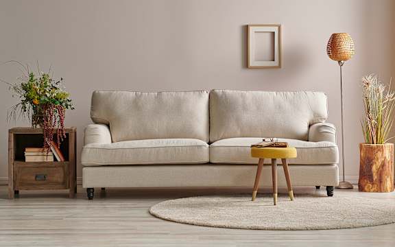 A beige sofa with a yellow side table in front of it.