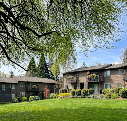 Apartment complex with green lawn and trees.
