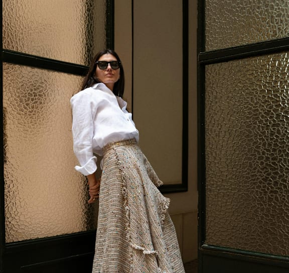 A woman wearing a white shirt and a patterned skirt.