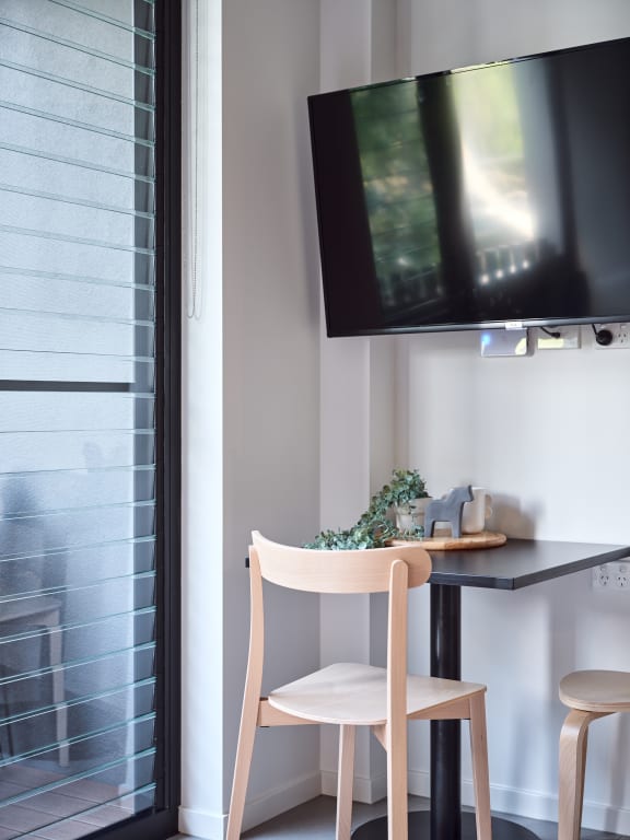 a small table with a chair and a tv on the wall