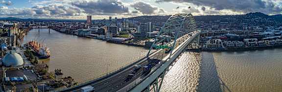 A bridge spans a river with a city in the background.