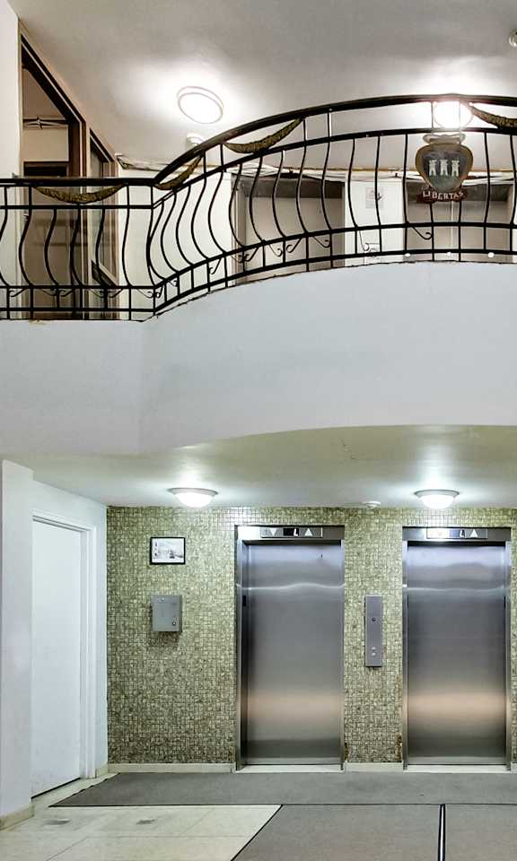 A hallway with a staircase and three elevators.