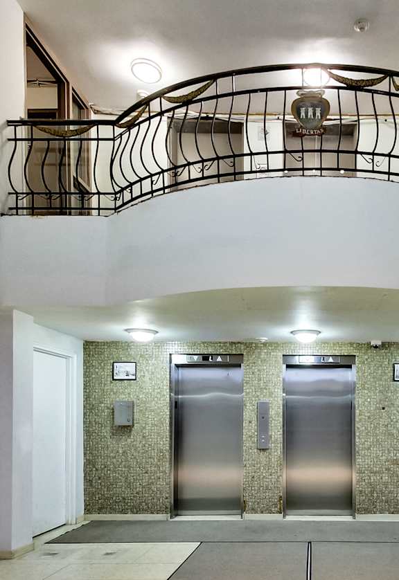A hallway with a staircase and three elevators.