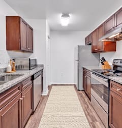 A kitchen with brown cabinets and a granite countertop.