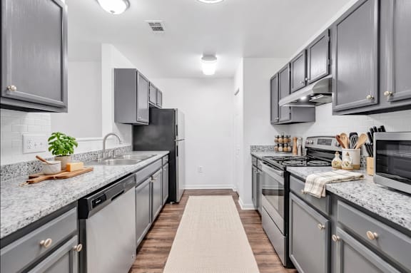 A kitchen with black cabinets and a marble countertop.