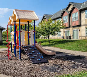 A playground with a slide, swings, and a climbing wall.