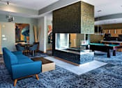 Thumbnail 8 of 26 - A comfortable blue couch in the community room looking into a large fireplace
