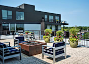 Thumbnail 21 of 26 - A modern patio with a fire pit and seating area.