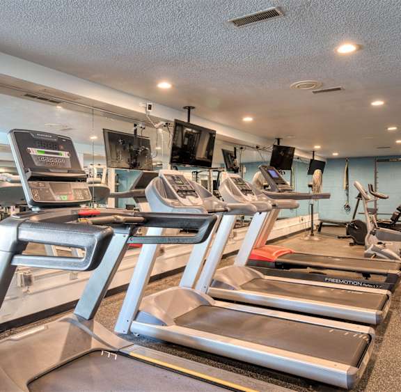 a gym with treadmills and other exercise equipment and a ceiling fan