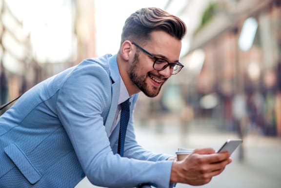A man in a blue suit is leaning forward while looking at his phone at Trend Design District, Dallas, Texas