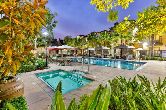 a swimming pool with tables and umbrellas at night at Capriana at Chino Hills, Chino Hills, CA