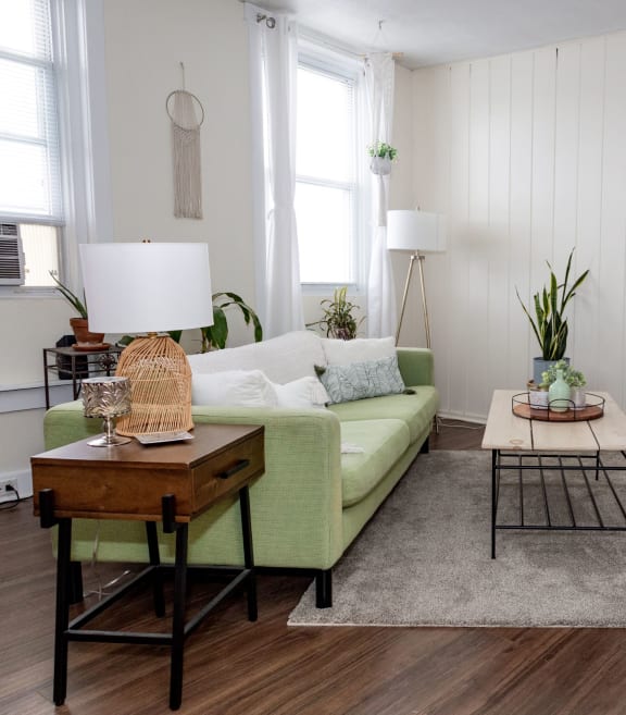 a living room with white walls and a green couch at University Commons in Pittsburgh, PA