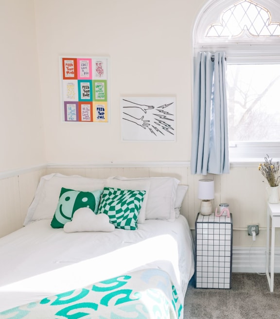 a bedroom with a bed and a desk and two windows at University Commons in Pittsburgh, PA