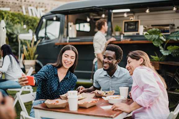 a group of people sitting at a table in front of a food truck