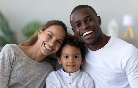 A family of three is smiling and posing together.