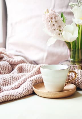 a bed with a pink blanket and a cup of coffee