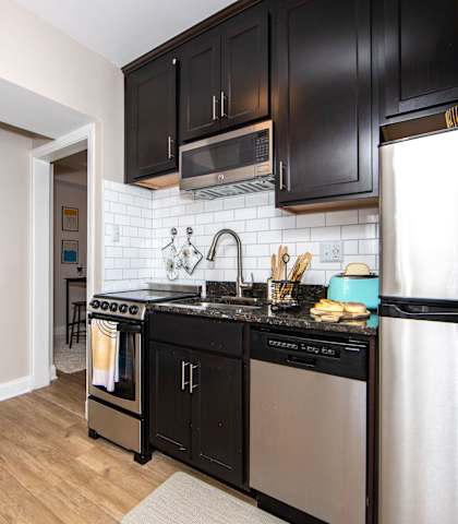 a kitchen with black cabinets and stainless steel appliances and a window