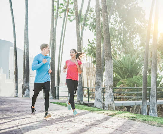 a man and a woman running on a sidewalk with palm trees in the background at Grandeville on Saxon, Orange City, Florida