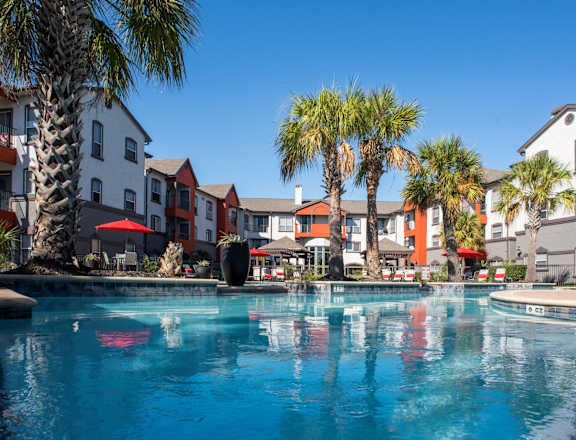 A swimming pool surrounded by palm trees and buildings.