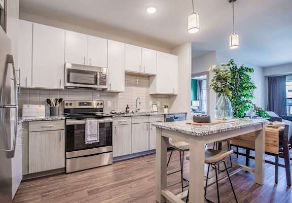 A modern kitchen with a stainless steel refrigerator, oven, and wooden flooring.