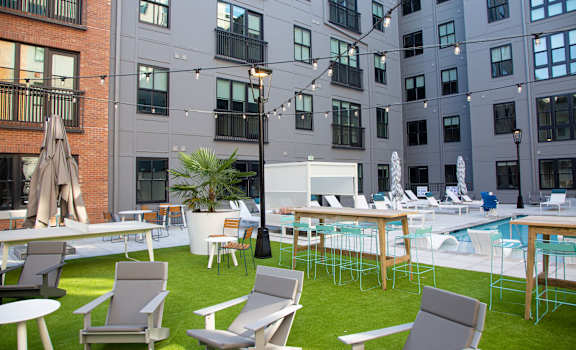 a grassy area with lounge chairs and tables and a pool in front of an apartment building at 511 Meeting, South Carolina, 29403