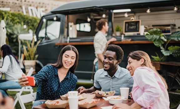 a group of people sitting at a table in front of a food truck