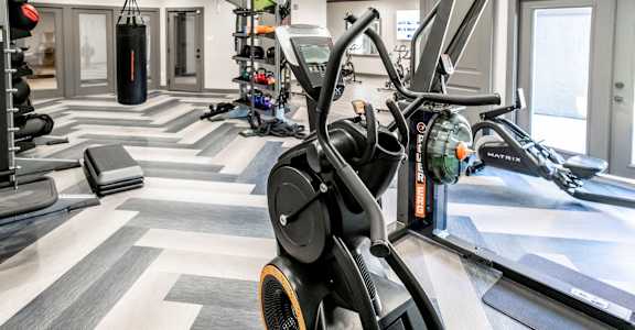 A gym with a variety of equipment including a treadmill, a punching bag, and a weight rack.